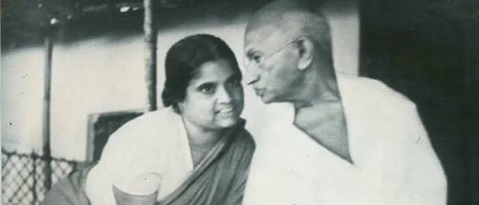 Durgabai Deshmukh in conversation with Mahatma Gandhi, the two of them seated close together and facing one another.
