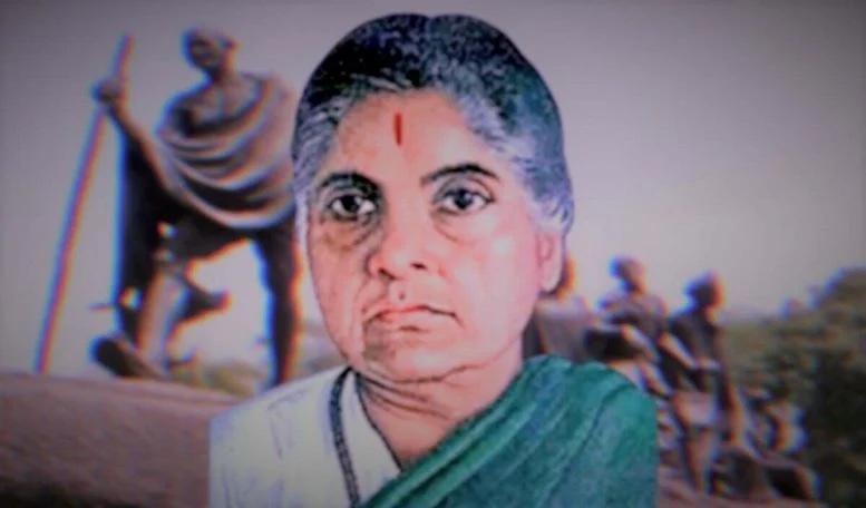 Portrait of Durgabai Deshmukh in later years, composited against a background showing a statue of Mahatma Gandhi with marching figures.