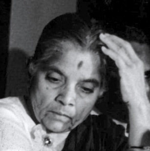 Black and white photograph of Durgabai Deshmukh in later years, her head slightly bowed and one hand raised to her forehead.